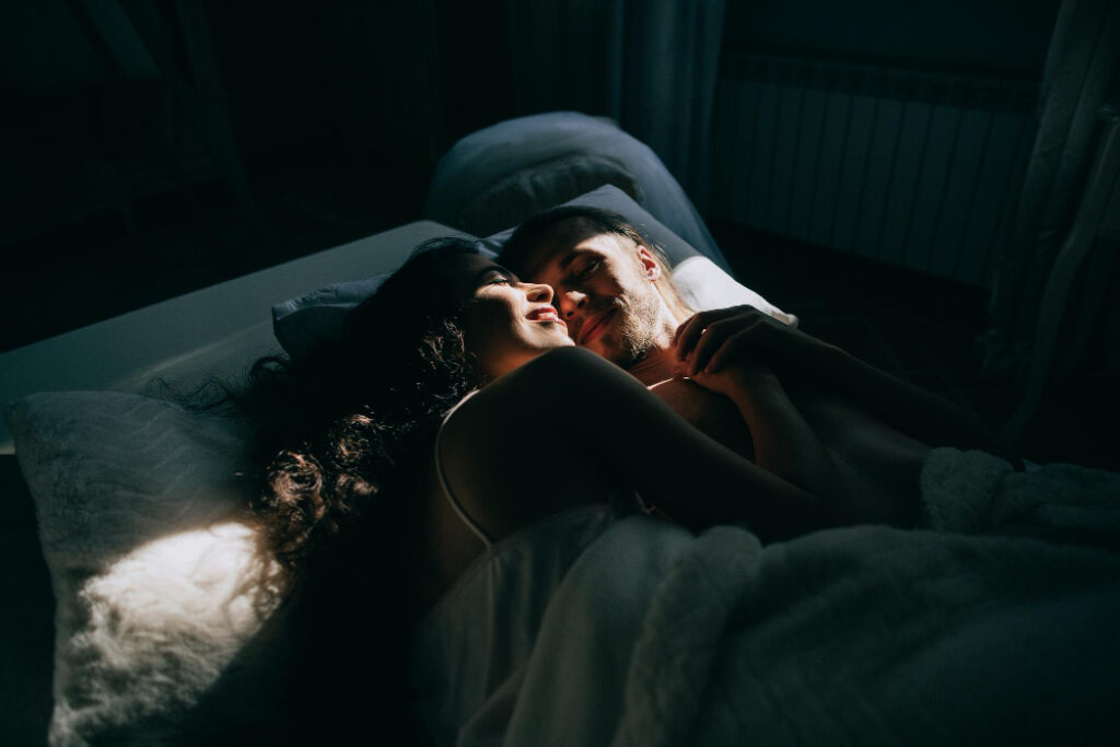 un homme et une femme dans un lit avec un rayon de soleil