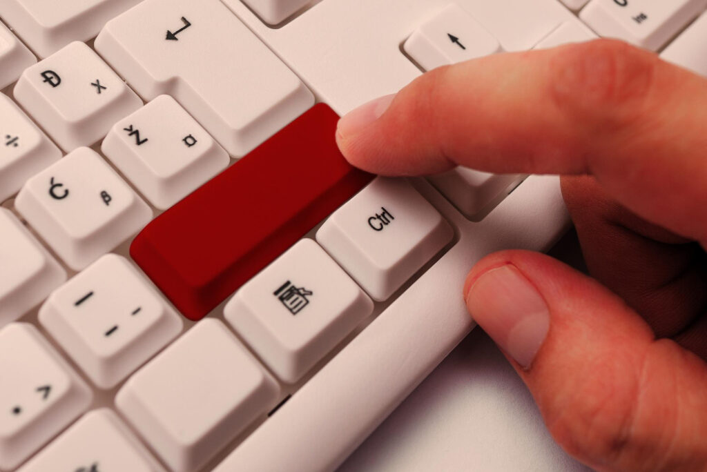 un doigt qui appuie sur une touche rouge d'un clavier d'ordinateur