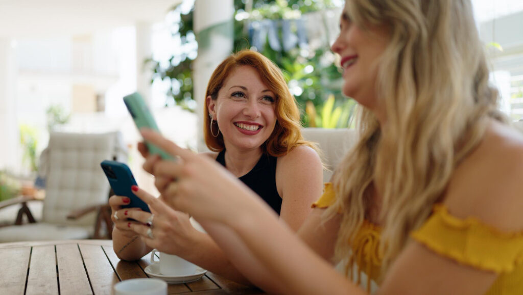 deux filles qui rigole et qui utilisent leur téléphones