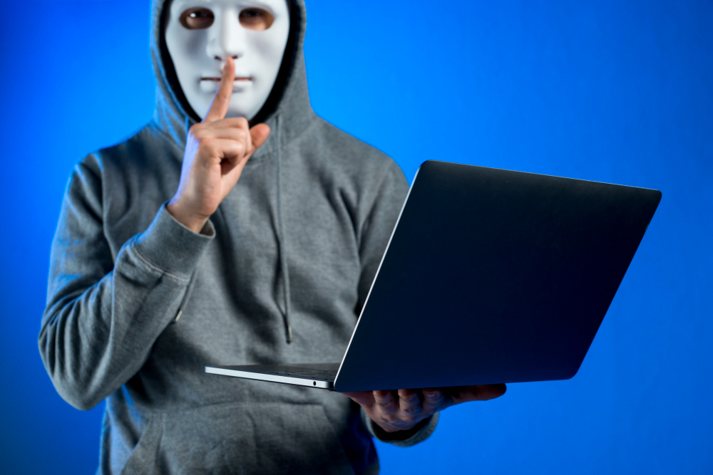 un home masqué avec un ordinateur dans les mains