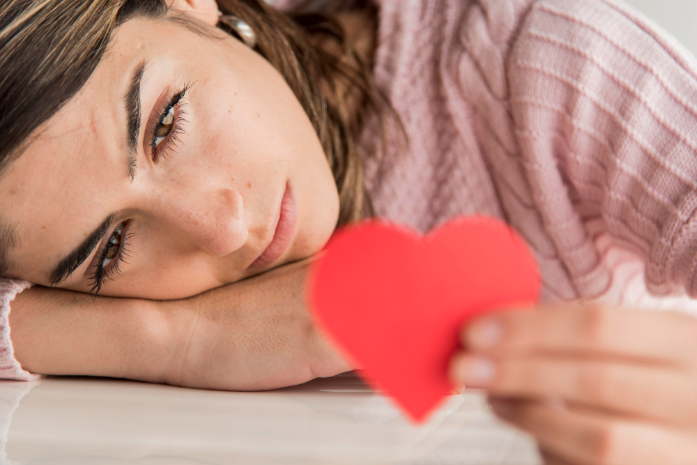 une femme triste avec un cœur en papier dans les mains