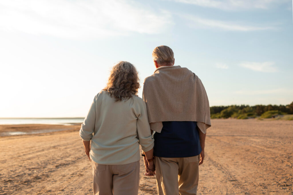 couple mature qui se tient par la main sur la plage