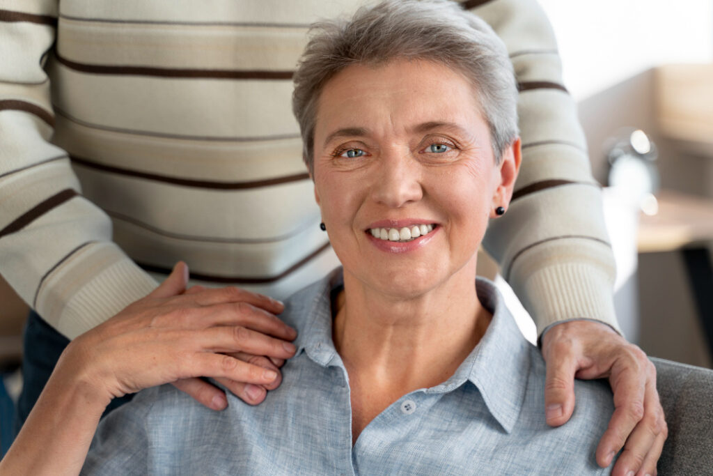 femme seniors assise avec les mains de son mari sur les épaules