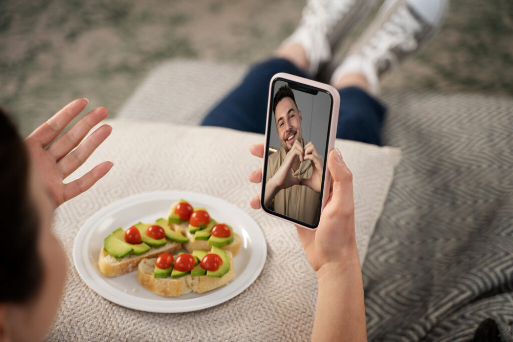 un homme fait un coeur avec ses mains à une femme en appel avec son téléphone