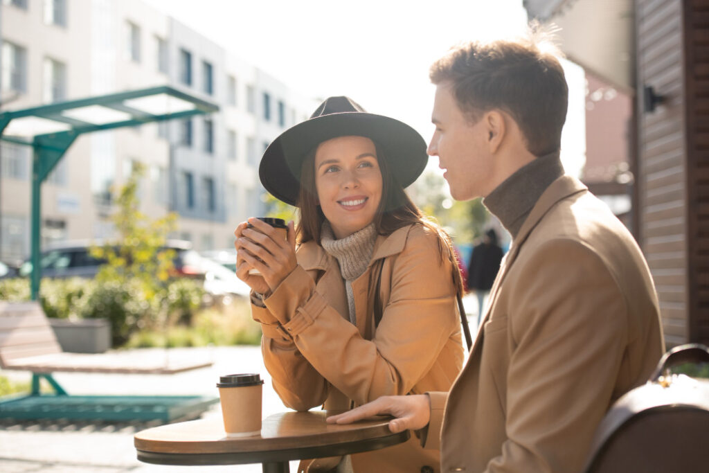 un homme et une femme buvant un café dehors en terrasse