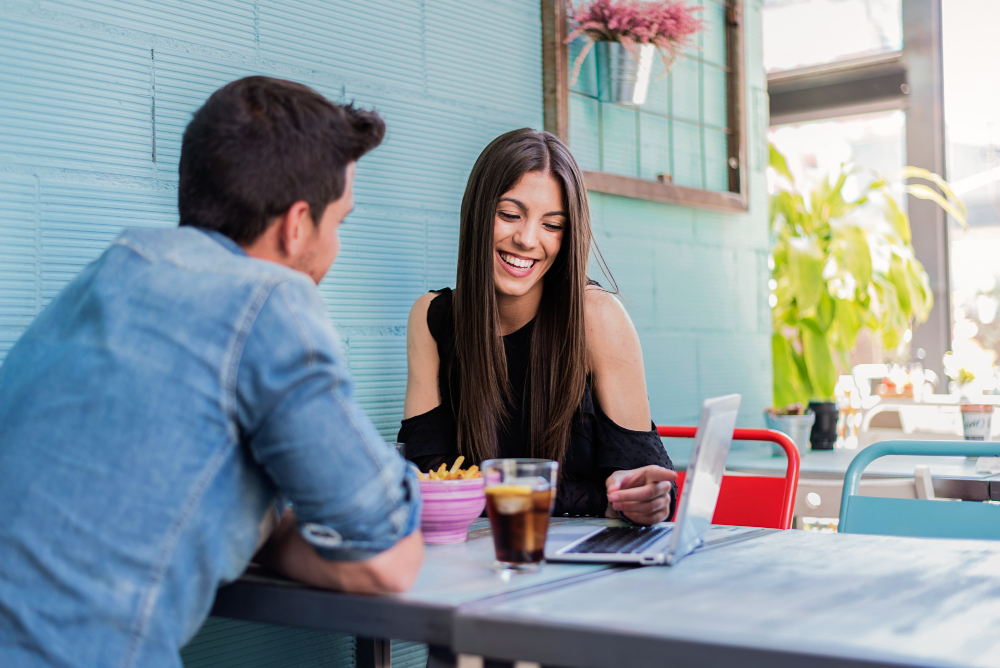 un couple en terrasse avec un ordinateur sur la table