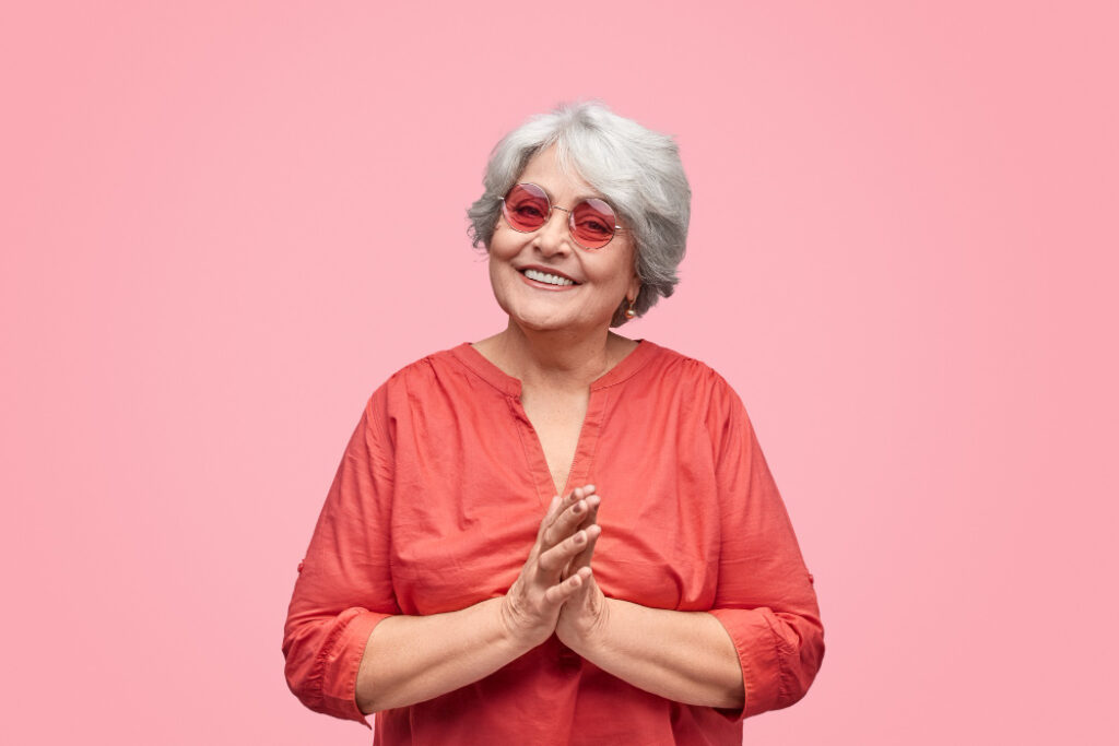 femme sénior avec des lunettes de soleil sur un fond rose