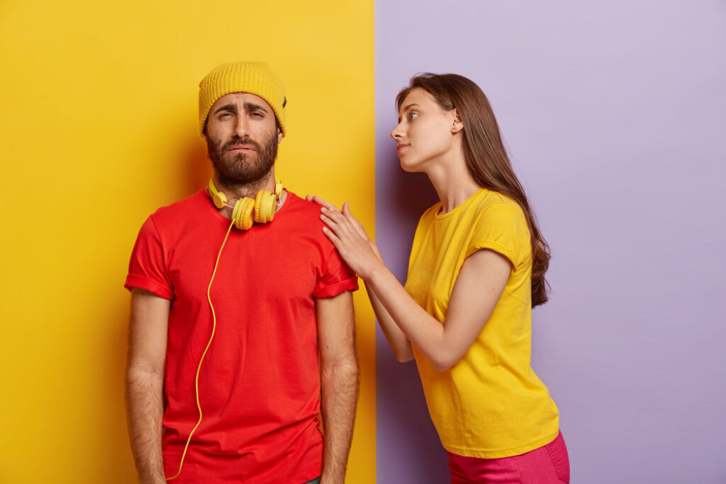 une femme tente de parler à un homme au regard triste devant un mur coloré