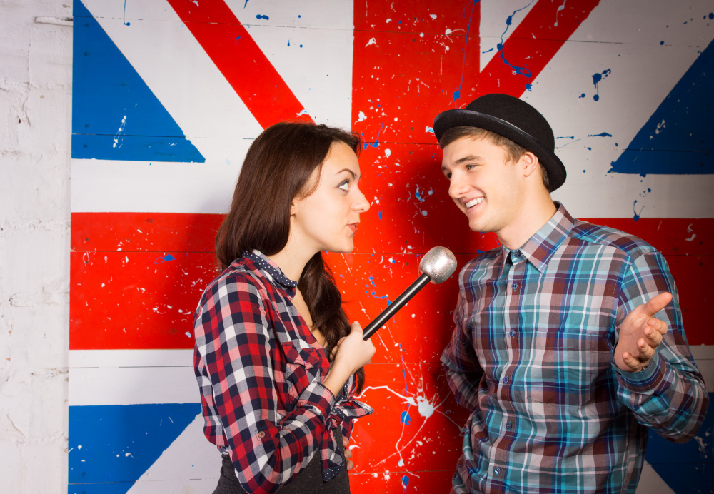 homme qui parle au micro d'une femme devant le drapeau anglais