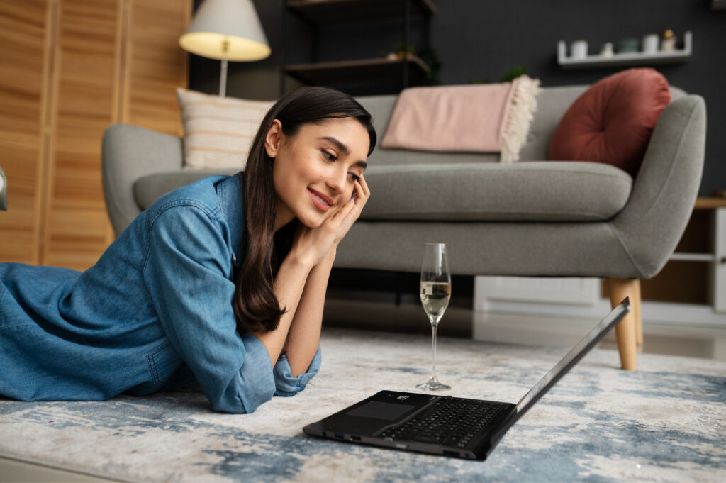 femme allongé avec un verre de vin devant son ordinateur