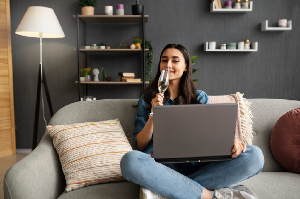 femme assise sur son canapé avec un verre de vin